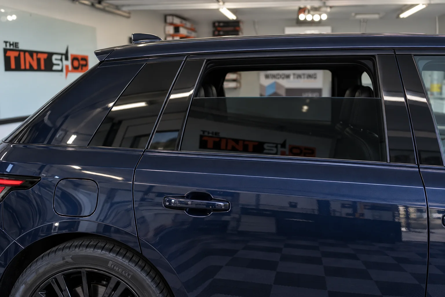 The clean top edge of tinted glass on a navy Range Rover Sport’s rear door, the window part way down